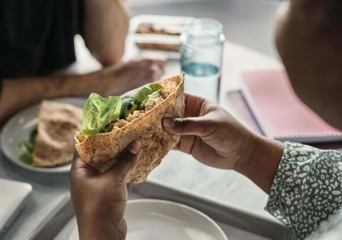 Une étudiante mange un wrap santé.